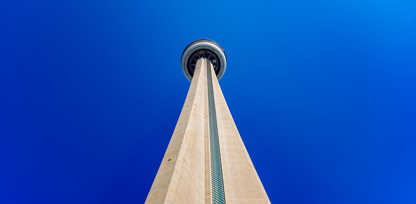 Architectural photograph looking up at the CN Tower against a blue sky by Jordan Licon