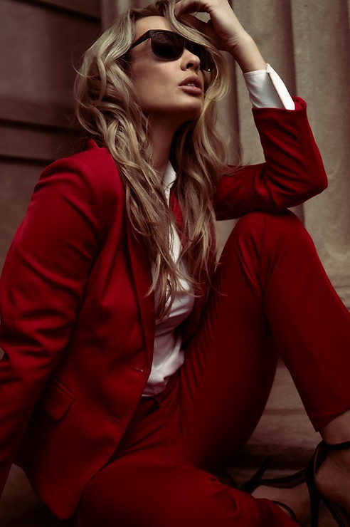 Woman in red pantsuit, sunglasses; fashion portrait