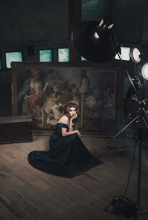 Woman in elegant dark gown sits in art studio; PORTRAIT; FASHION