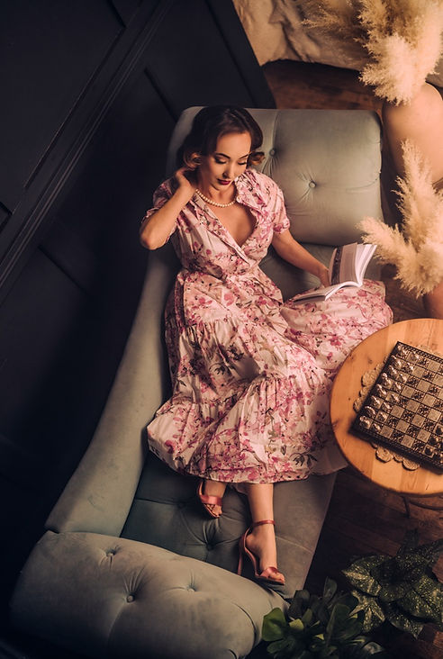 Woman in pink floral dress relaxes on couch