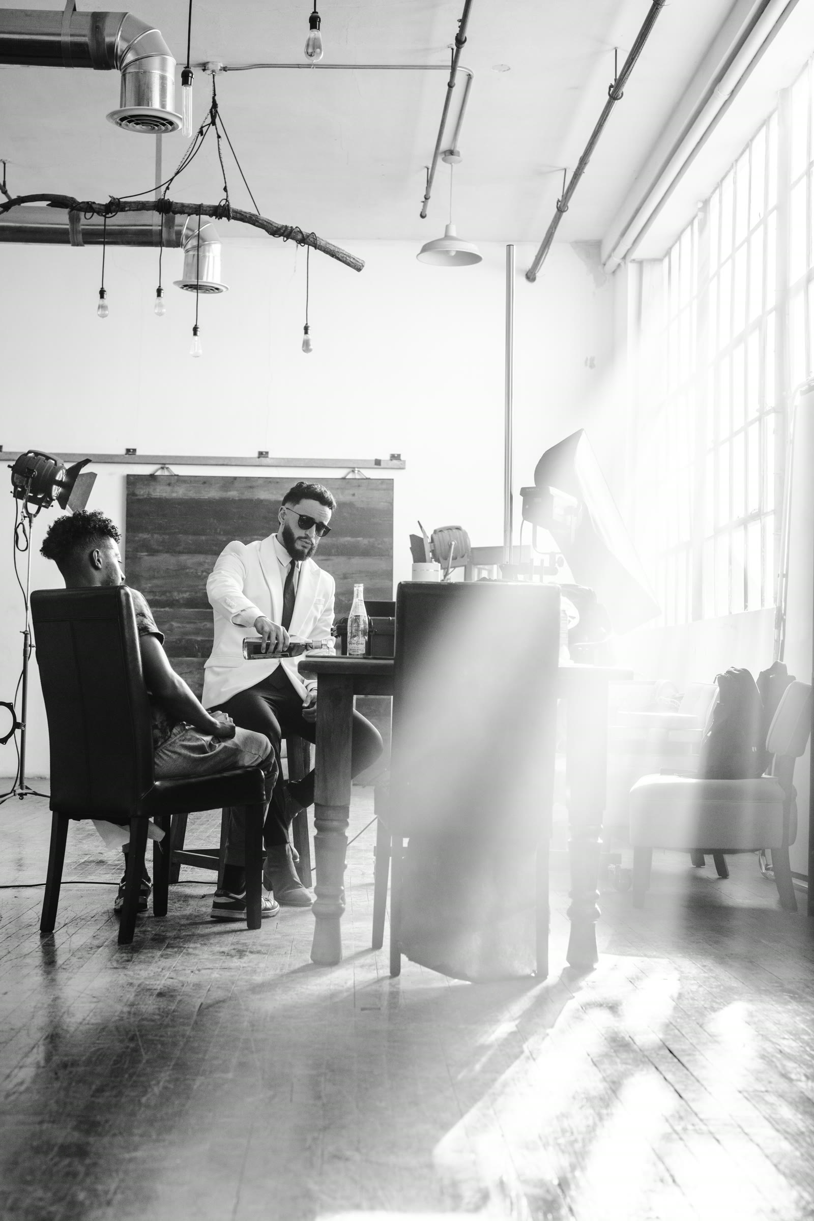 Black-and-white behind-the-scenes studio scene with a photographer directing a portrait subject