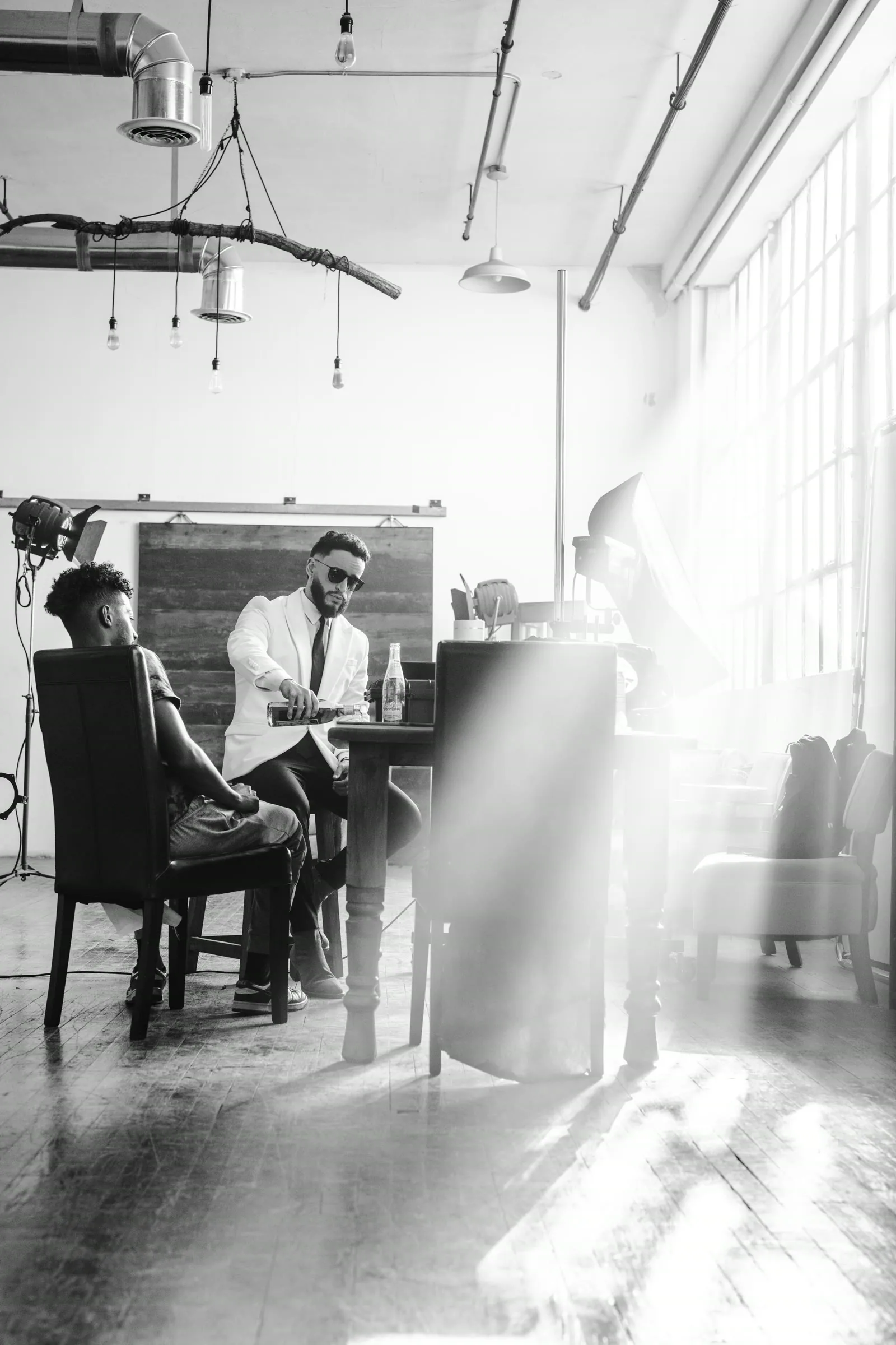 Black-and-white behind-the-scenes studio scene with a photographer directing a portrait subject